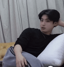 a young man in a black shirt is laying on a couch with a pillow