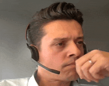 a man wearing a headset and a ring on his finger looks at the camera