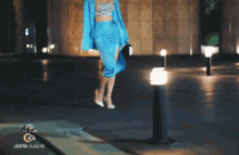 a woman in a blue dress is walking in front of a sign that says ' g & g ' on it