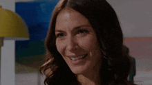 a close up of a woman 's face smiling in front of a yellow lamp .