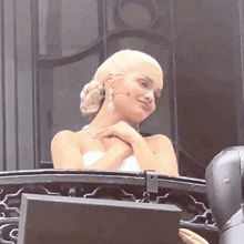 a woman in a white strapless dress is standing on a balcony