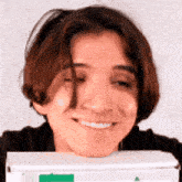 a young man is smiling while holding a pizza box .