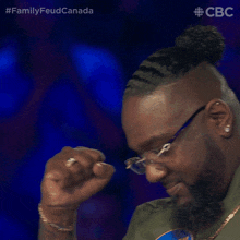 a man wearing glasses and a ring is watching a family feud on cbs