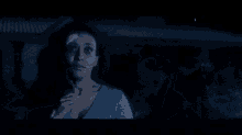 a woman in a blue dress is standing next to a man in a blue shirt in the dark .