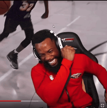 a man wearing headphones and a red shirt with the number 32 on it is smiling