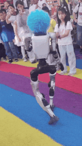 a robot with a blue pom pom on its head walks down a colorful carpet