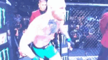 a man with a tattoo on his chest is standing in a boxing ring .