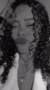 a black and white photo of a woman with curly hair and a necklace