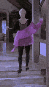 a woman in a purple dress is standing in a room