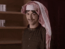 a man wearing a head scarf and a black shirt smiles for the camera