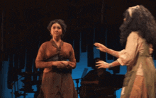two women are dancing on a stage with a man playing a piano in the background