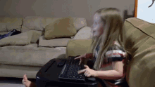 a little girl is typing on a keyboard on a table