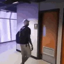 a man with a backpack is walking through a hallway towards a bathroom .
