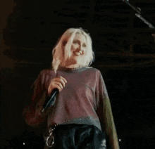 a woman in a colorful shirt is dancing on a stage in a dark room .