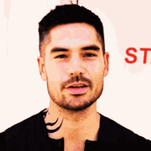 a man with a tattoo on his neck is standing in front of a sign that says st.