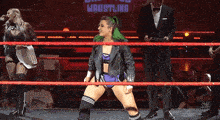 a woman in a wrestling ring with the word wrestling on the wall behind her