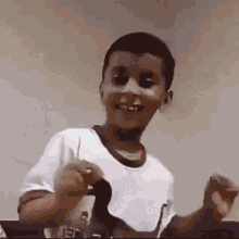 a young boy in a white shirt is smiling and holding something in his hand