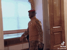 a man in a military uniform is walking down a hallway with a tiktok watermark on the bottom