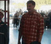 a man in a red plaid shirt stands in front of a crowd