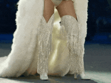 a woman wearing a white fur coat and white fringe boots