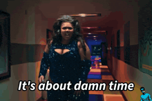 a woman standing in a hallway with the words it 's about damn time