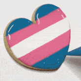 a heart shaped cookie is being decorated with a transgender flag design