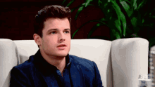 a young man in a blue jacket is sitting on a couch