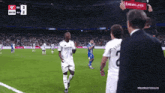 a man holding a sign that says emirates stands in front of a soccer player