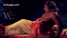 a shirtless man is laying on a bed with a woman in a red dress .