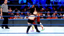 two women are wrestling in a wrestling ring with a referee watching