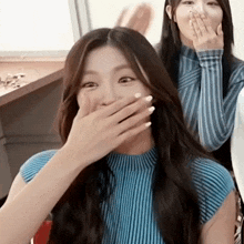 a woman in a blue striped shirt is covering her mouth