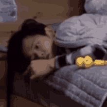 a woman is laying on a bed with a watch on her wrist and a yellow object in her hand .