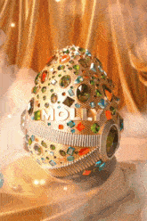 a gold egg with molly written on it is sitting on a table