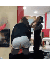 two women are standing next to each other in a living room with a fireplace .