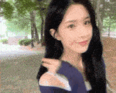 a woman with long black hair is walking down a sidewalk in a park .