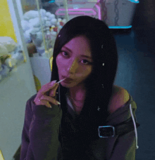 a woman with long black hair is eating a lollipop and looking at the camera