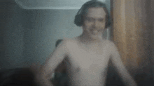 a shirtless man wearing headphones is standing in front of a computer screen .