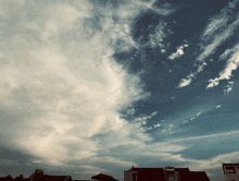 a blue sky with white clouds and a few buildings
