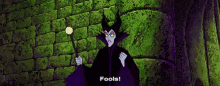maleficent from the sleeping beauty is holding a magic wand and saying fools .