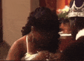 a woman is breastfeeding a baby while a man wearing a crown is standing next to her .