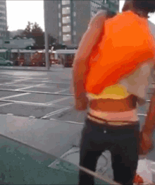 a man in an orange vest is standing on the street