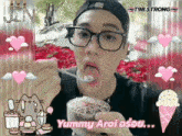 a man with glasses is eating an ice cream cone with the words yummy aroi on it