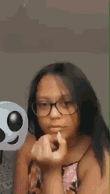 a young girl wearing glasses is applying lipstick .
