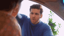 a man in a blue sweater is talking to a woman in a car