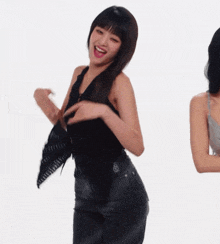 a woman in a black top and black pants is smiling and dancing