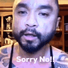 a man with a beard and tattoos is saying sorry no .