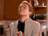 a young man wearing a grey jacket and a black shirt looks up at something