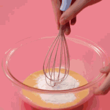 a person is pouring whipped cream into a bowl with a red spatula .