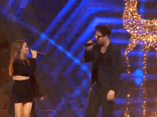 a man wearing sunglasses is singing into a microphone with a christmas tree in the background