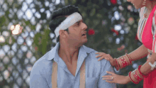 a man with a bandage on his head is being comforted by a woman in a red dress
